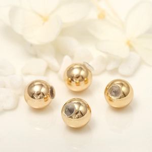Détail de quatre boucles d'oreilles boules dorées avec fermoirs en silicone transparent