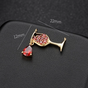 Macro detail of a 14k gold plated wine glass pendant with red zircon and drop gem
