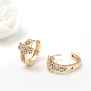 Elegant gold cross huggie earrings with shimmering white zirconia stones on white background
