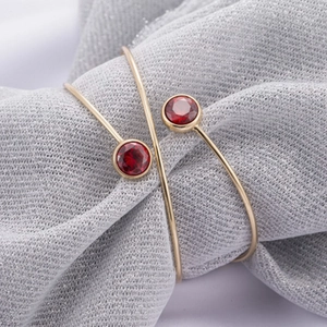 14k vergulde verstelbare open armband met rode edelstenen op een zijden achtergrond