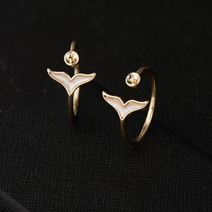 Golden open hoop earring featuring a white enamel whale tail pendant design