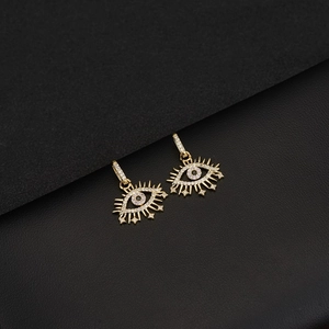 Detail of 14K gold evil eye earrings with sunburst rays and white zircon on leather base