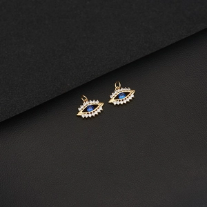 Detailed close-up of two 14K gold Evil Eye pendants with blue zircon and pavé crystals
