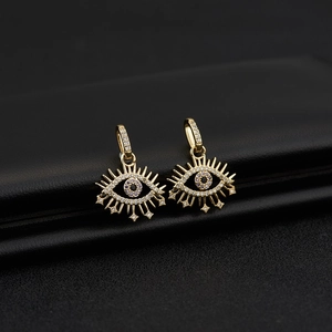Macro shot of gold-plated evil eye earrings with white zircon pavé and star details