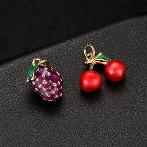 Enamel strawberry and cherry charms with gold alloy base on a black leather background