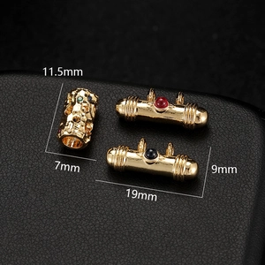 Macro view of 14K gold-plated cylindrical charms with micro-pave zircons and gemstones
