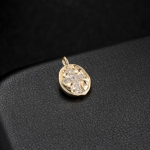 Close-up of golden oval pendant with zircon cross on black leather background
