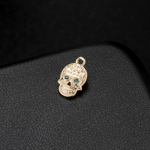 14K gold skull pendant with green rhinestones and engraved texture for jewelry making
