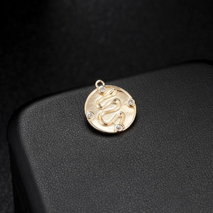 Macro shot of 14K gold snake pendant with micro-paved zircons on black background