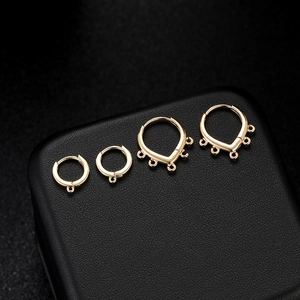 Minimalist gold-plated earring hoops and DIY jewelry findings on black leather display