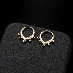 Minimalist gold U-shaped earrings with five hanging loops on black leather background