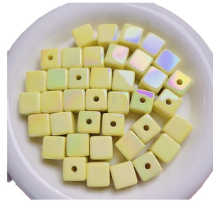 Lustrous yellow UV coated cube beads in a white ceramic dish for DIY jewelry making