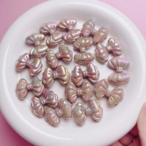 Detailansicht irisierender cremiger rosa Schleifenperlen für DIY-Schmuck in weißer Schale