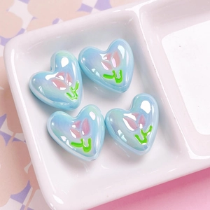Detail of light blue heart beads with pink tulip patterns and iridescent finish