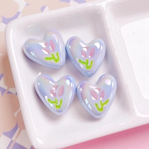 Macro shot of iridescent heart beads with pink tulip pattern for DIY jewelry crafts