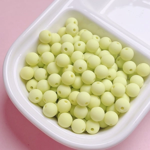Macro detail of 6/8mm matte rubber-finish light yellow round beads in a divider tray