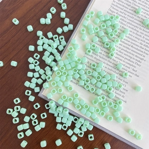 Mint green square acrylic beads for DIY jewelry making scattered on a wooden desk