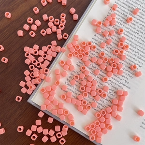 Close-up of pastel pink acrylic square beads on a wooden table for DIY jewelry making