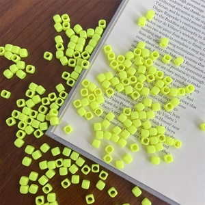 Macro shot of bright yellow square acrylic beads with large holes on a wooden desk