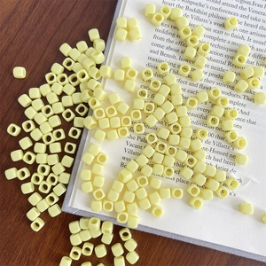 Close-up of cream yellow acrylic cube beads on a book for DIY jewelry making