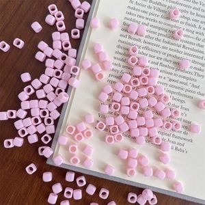Macro shot of pink macaron square acrylic beads with center holes on a wooden desk