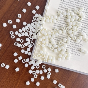 Macro shot of white square acrylic beads on a wooden table for DIY jewelry making crafts
