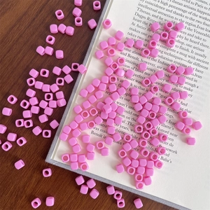 Macro detail of pink square acrylic beads with center holes on vintage book for DIY jewelry