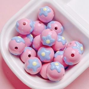 Macro shot of pink heart beads with blue flowers in a white tray for DIY jewelry projects