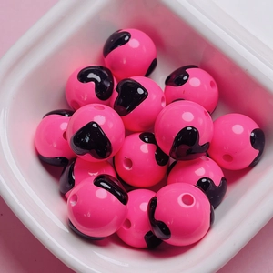Macro detail of pink acrylic beads with black heart patterns for DIY jewelry making