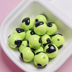 Macro shot of neon green round beads with black heart patterns for DIY jewelry making
