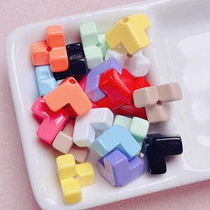 Bunte Acrylperlen in Tetris-Form für DIY-Schmuck in weißen Fächern auf rosa Hintergrund