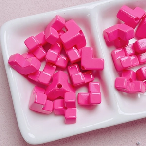 Nahaufnahme von leuchtend rosa Acrylperlen mit diagonalen Löchern in einer weißen Schale