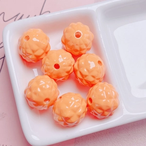 Close-up of orange acrylic pineapple beads with geometric facets for DIY jewelry making