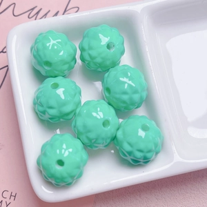 Close-up of mint green acrylic beads with geometric texture in a white tray