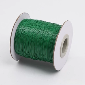 Detalle de cordón encerado verde de 1-2mm para creación de joyas en carrete blanco