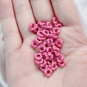 Macro detail of small pink wave-shaped alloy spacer beads with glossy glazed texture