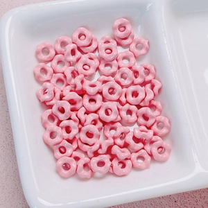 Close-up of pink glazed flower-shaped alloy spacer beads for DIY jewelry making
