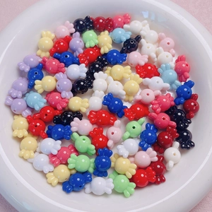 Cuentas acrílicas de colores con forma de caramelo para joyería DIY en plato blanco