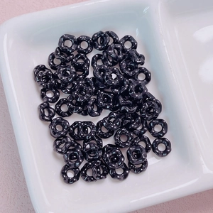 Close-up of black flower-shaped spacers with white polka dots for DIY jewelry making