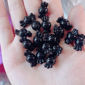 Detalle macro de cuentas acrílicas negras brillantes con forma de caramelo para bisutería