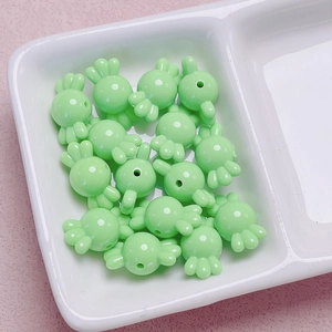 Detalle de cuentas de acrílico verde claro en forma de caramelo para joyería artesanal