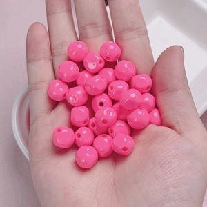 Macro shot of 10mm glossy bright pink acrylic beads held in hand for DIY jewelry making