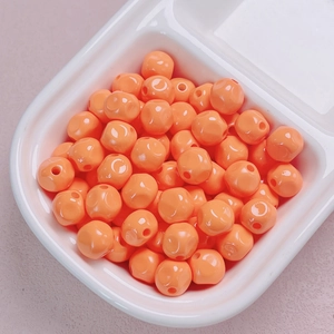 Macro view of 10mm bright orange lacquered acrylic beads for DIY jewelry making and crafts