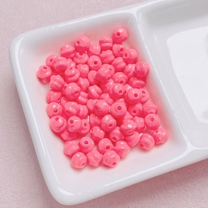 Dettaglio di perle in acrilico rosa lucido con fori per la creazione di gioielli fai da te