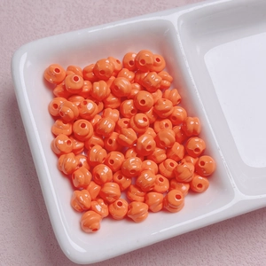 Primo piano di perline a spirale in acrilico arancione brillante con foro centrale per DIY