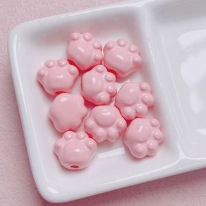 Detalle macro de cuentas de pata de gato de acrílico rosa con agujeros para joyería DIY