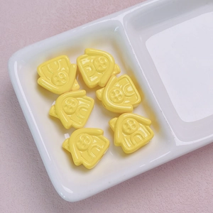 Detail shot of bright yellow house-shaped acrylic beads with fine architectural patterns