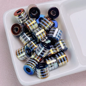 Macro shot of colorful striped cylindrical resin beads in a ceramic tray for DIY jewelry