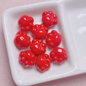 Primer plano de nueve cuentas de acrílico con forma de pata de gato roja en plato blanco