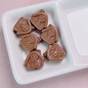 Detail of 6 cute brown house acrylic beads in a white dish for DIY jewelry crafting